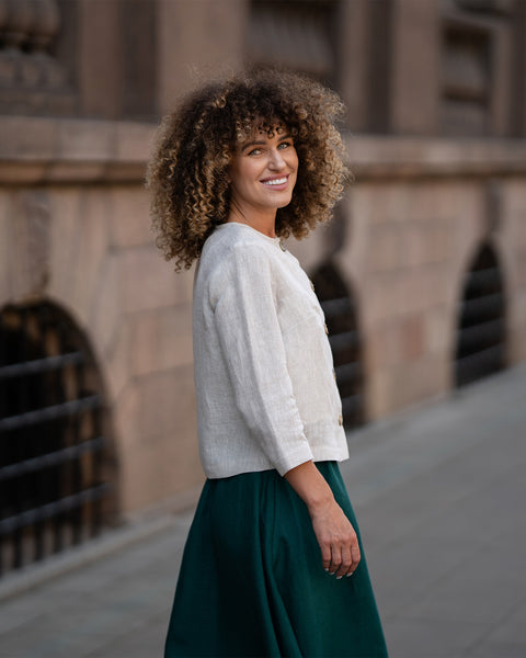 Un modelo que lleva una chaqueta Alice de lino beige natural con botones, con un corte holgado, mangas de tres cuartos y un diseño minimalista
