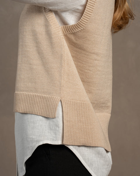 El lateral del chaleco tejido de lana merina ISLA en color beige. La parte delantera es un poco más corta que la trasera, como se ve en la imagen. El chaleco tiene aberturas a ambos lados.