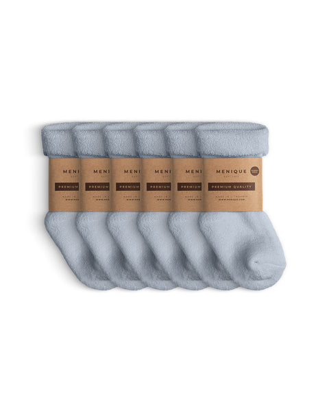 Juego de seis pares de calcetines infantiles de estilo sherpa en azul claro, agrupados con envoltorios de papel kraft ecológico de Menique que dicen ‘Calidad Premium’.