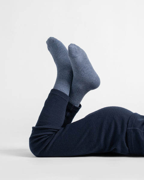 Child lying on the floor in navy blue leggings with lower legs bent upward, wearing matching dark blue socks.