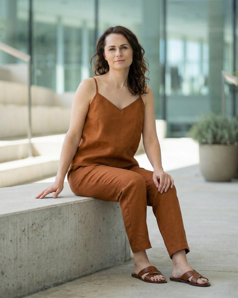 Woman wearing almond brown linen camisole top and matching linen pants, breathable lightweight summer co-ord set styled outdoors in modern setting
