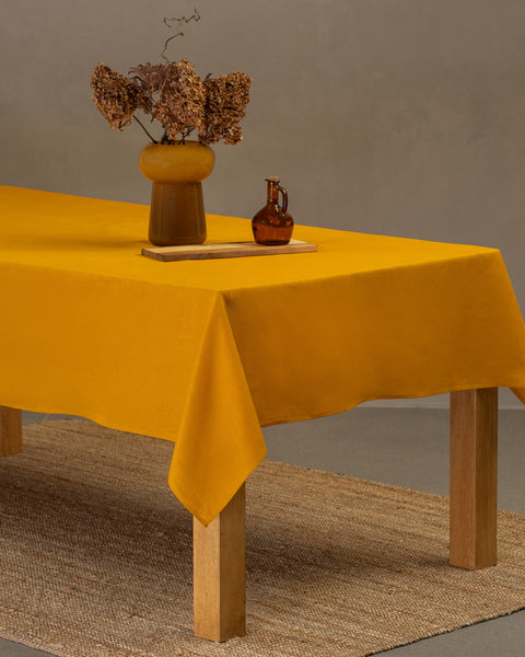 Mantel de lino amarillo vibrante con centro de mesa floral para un ambiente cálido y acogedor en el comedor.