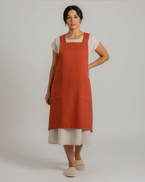 Mujer con un delantal rojo canela sobre una camisa blanca sobre un fondo liso