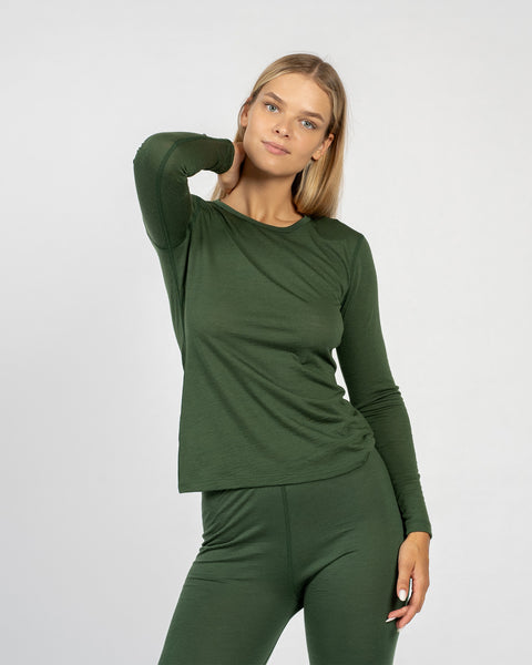 La camiseta de manga larga para mujer de lana merina en verde oscuro de menique combinada con los pantalones verdes oscuros de menique, vista desde el frente.