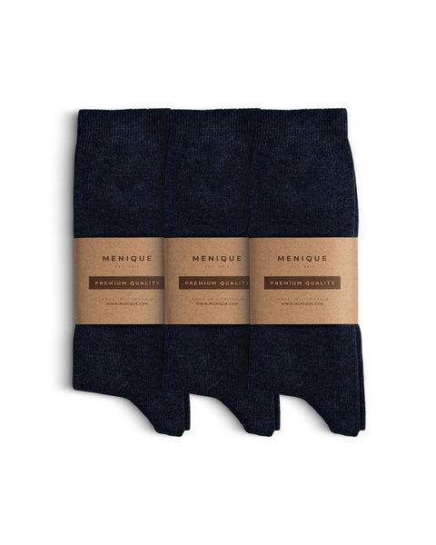 Tres pares de calcetines de algodón para hombre en azul oscuro dispuestos uno al lado del otro con etiquetas de papel marrón de Menique marcadas como ‘Calidad Premium’.