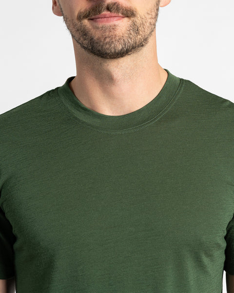 Primer plano de una camiseta menique verde oscuro, mostrando la textura de la tela de merino y el estilo de cuello redondo.
