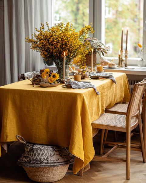 Mantel de lino amarillo vibrante con centro de mesa floral para un ambiente cálido y acogedor en el comedor.