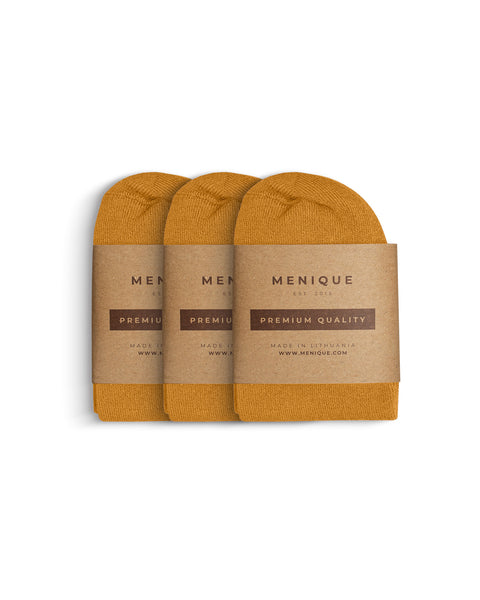 Tres pares de calcetines de bambú para mujer en amarillo mostaza, doblados uno al lado del otro y empaquetados con etiquetas de papel kraft marrón de Menique marcadas con ‘Calidad Premium’.