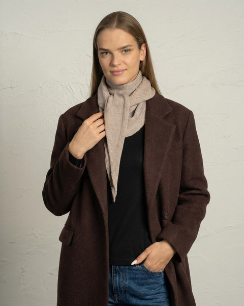 Pañuelo de punto de lana merina color beige cremoso envuelto alrededor del cuello de una mujer.