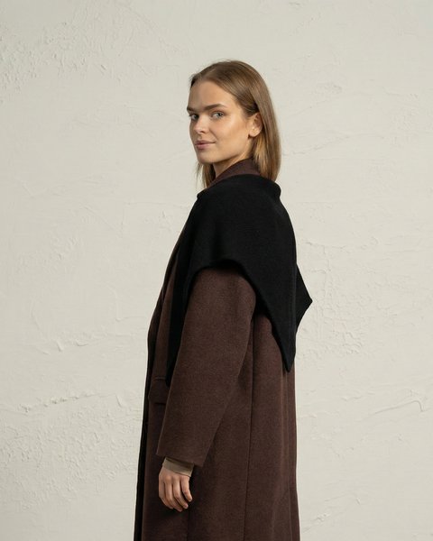 Vista lateral de una mujer que lleva una bandana de punto de merino negra como chal para el hombro.