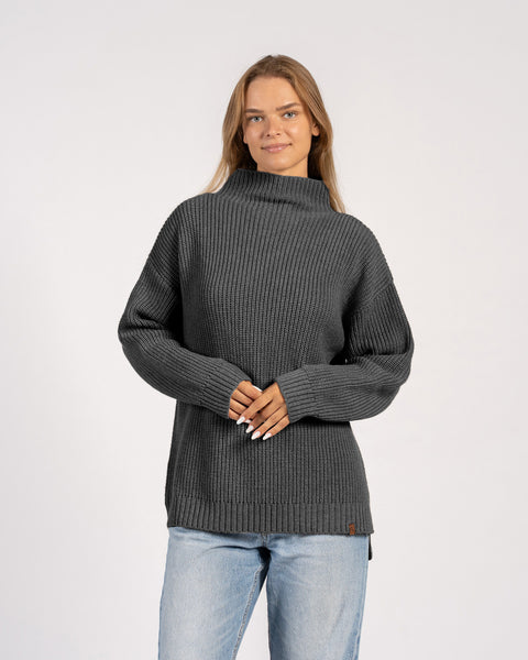 Vista frontal de mujer con suéter de lana merina oscura tejido, con cuello alto.