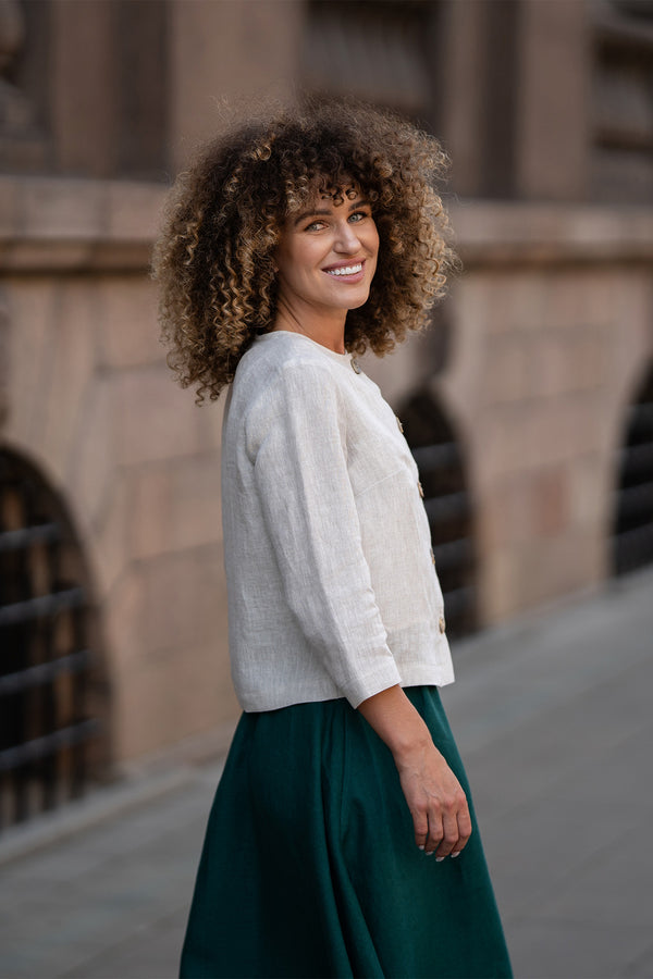 Un modelo que lleva una chaqueta Alice de lino beige natural con botones, con un corte holgado, mangas de tres cuartos y un diseño minimalista