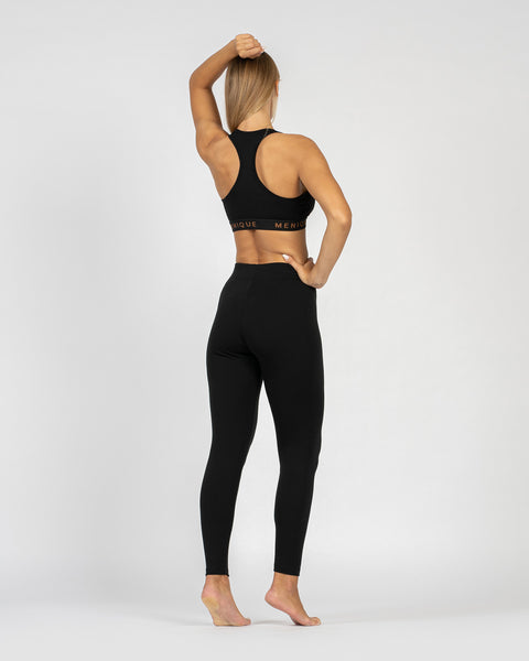 El sujetador deportivo para mujer de menique en lana merina de 160 g/m² y los pantalones ajustados en tela de 250 g/m², color negro, vista trasera.