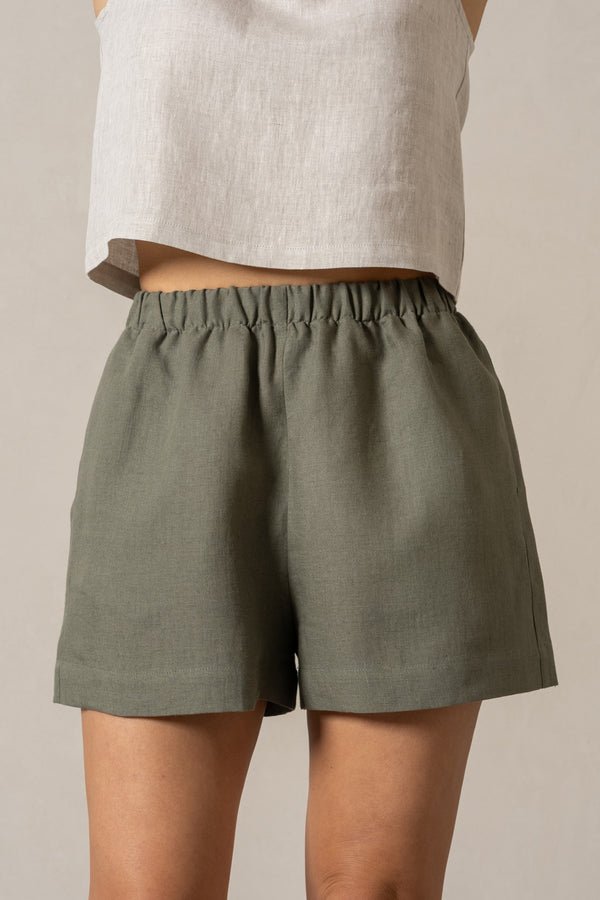 Pantalones cortos de lino con cintura elástica en color verde piedra. Pantalones cortos informales de talle alto con bolsillos y cintura elástica.