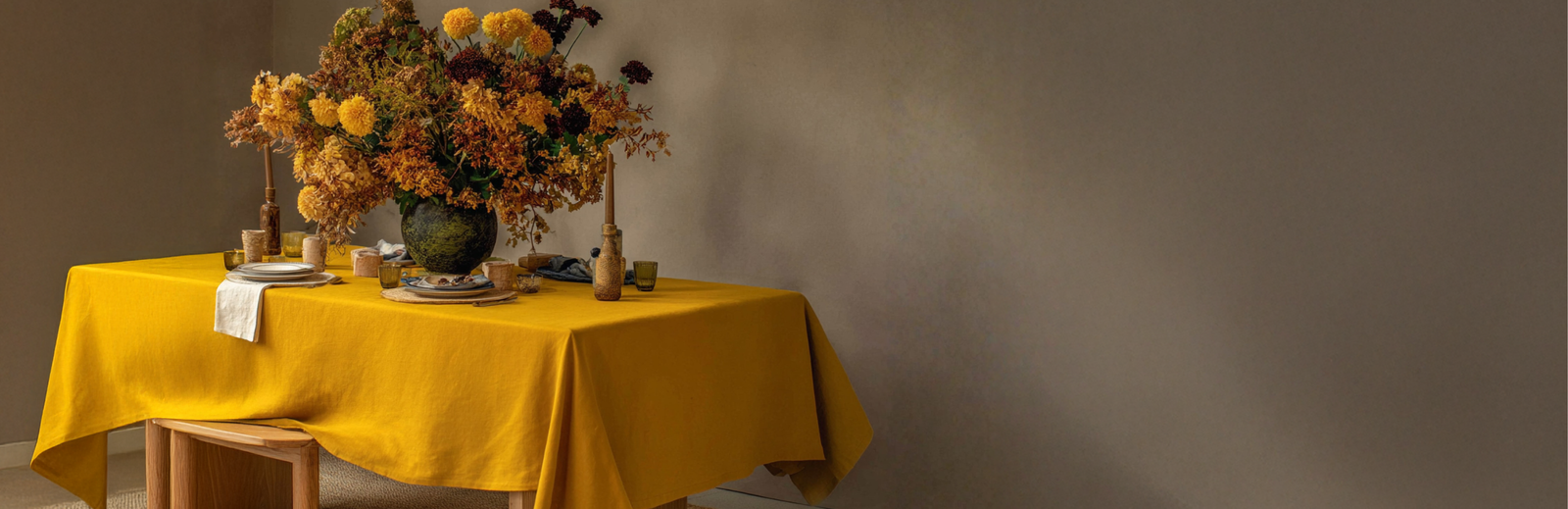 Mantel de lino en amarillo mostaza sobre una mesa de comedor con arreglo floral otoñal