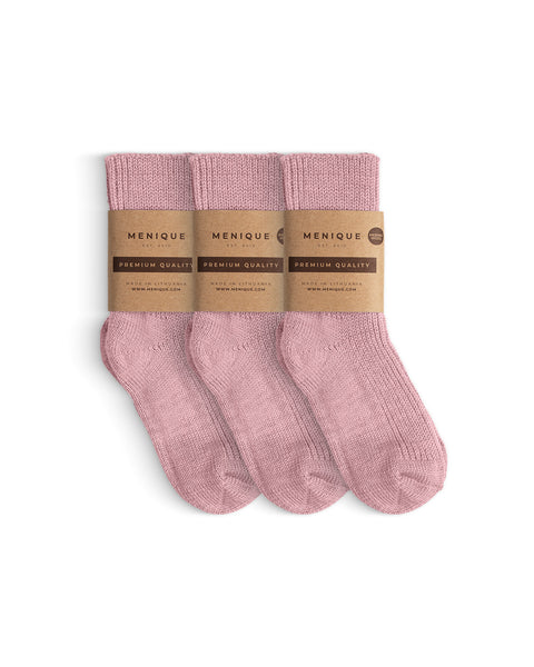 Three pairs of children’s ribbed thick socks in a soft pink color, neatly folded with brown paper labels that read ‘Menique – Premium Quality.