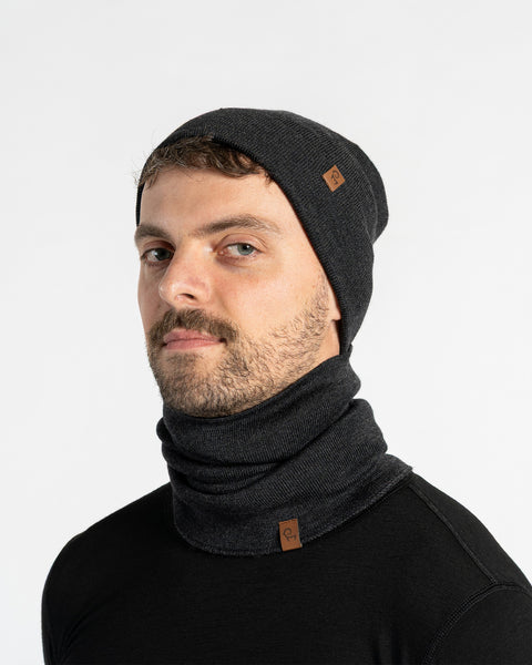 Hombre con un gorro de punto gris oscuro y bufanda sobre un fondo gris claro