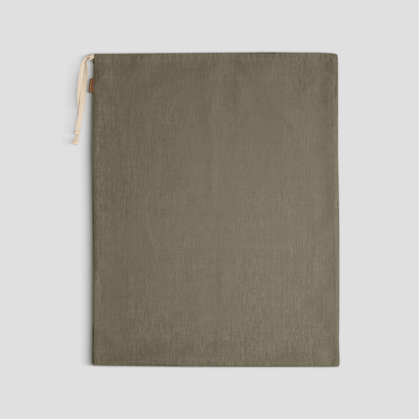 Una maleta abierta está ordenadamente llena con cuatro bolsas de tela con cordón de diferentes tamaños y colores (dos verde oliva y dos beige claro) sobre una superficie de madera.