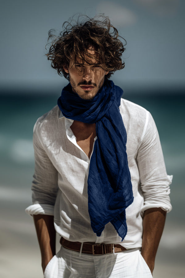 Hombre con camisa blanca y bufanda azul en una playa