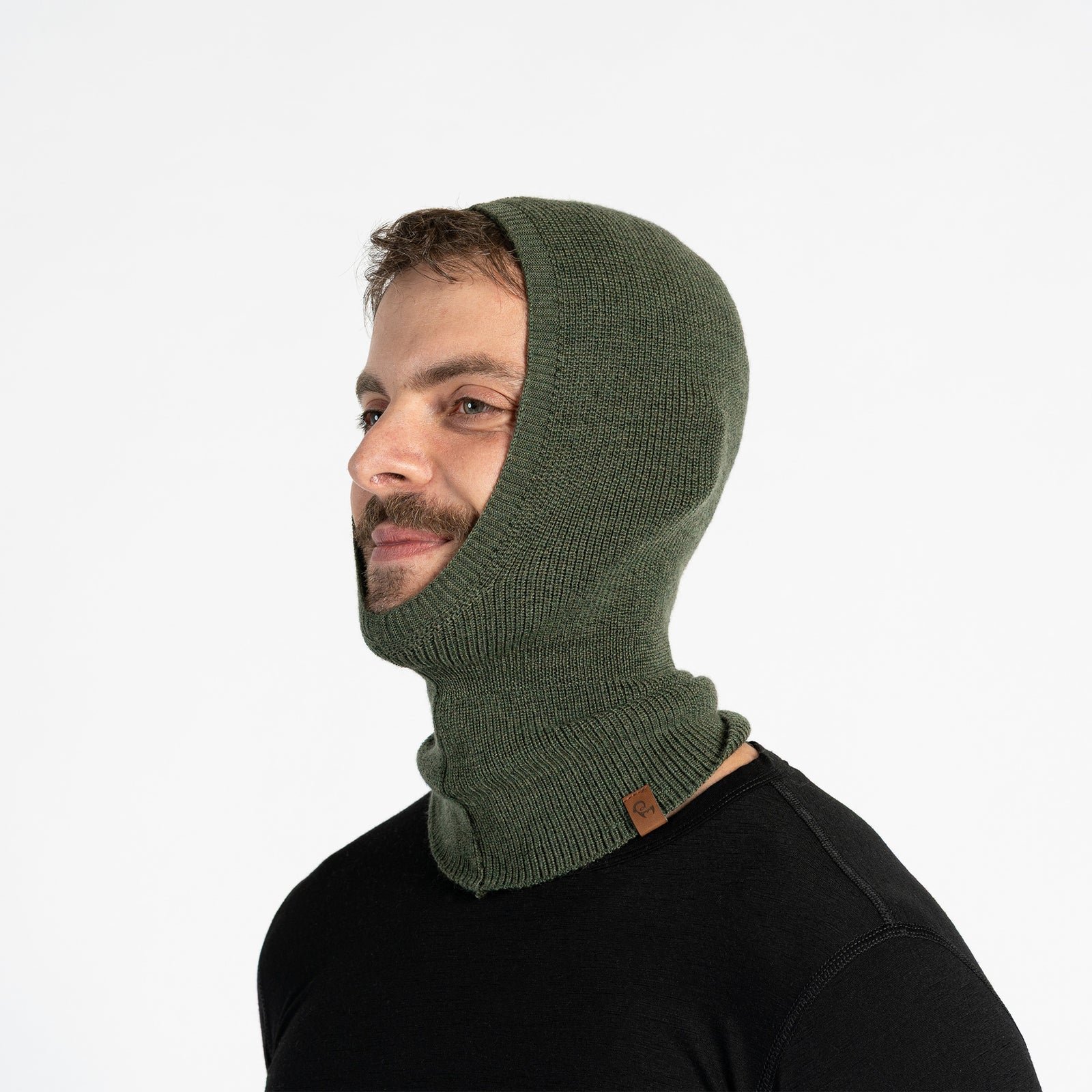 Hombre sonriente en las pistas de esquí con un pasamontañas interior de lana merina gris oscuro bajo una chaqueta de esquí azul y gafas.