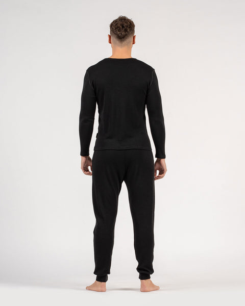 El conjunto para hombre de menique, compuesto por camiseta de manga larga de lana merina de 250 g/m² y pantalones deportivos tipo jogger en color negro.