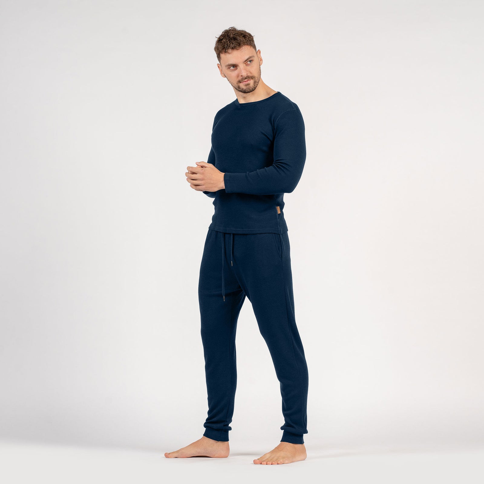 El conjunto para hombre de menique, compuesto por camiseta de manga larga de lana merina de 250 g/m² y pantalones deportivos tipo jogger en color negro.