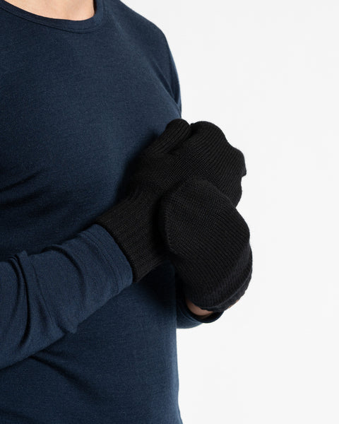 A person wearing a dark blue long-sleeved shirt and black menique mittens. The person is holding their hands together.