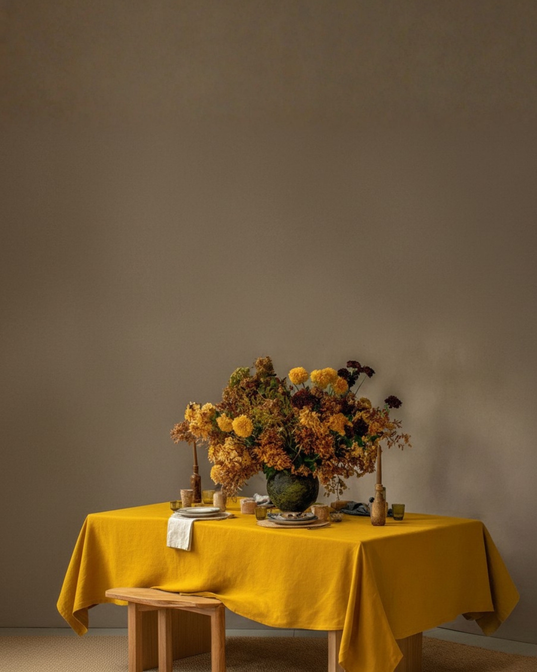 Mantel de lino en amarillo mostaza sobre una mesa de comedor con arreglo floral otoñal
