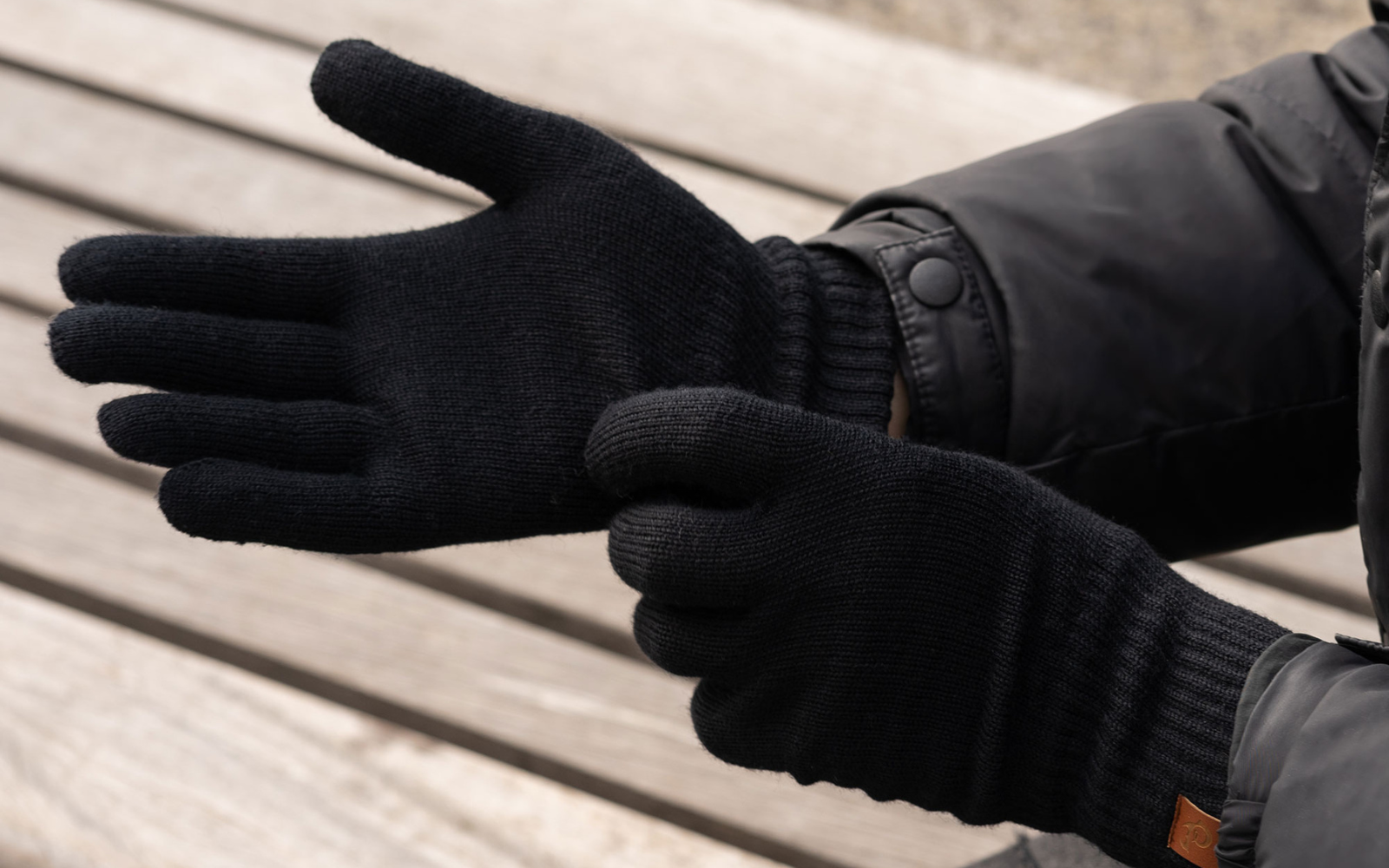 Un hombre poniéndose guantes negros de lana merina.