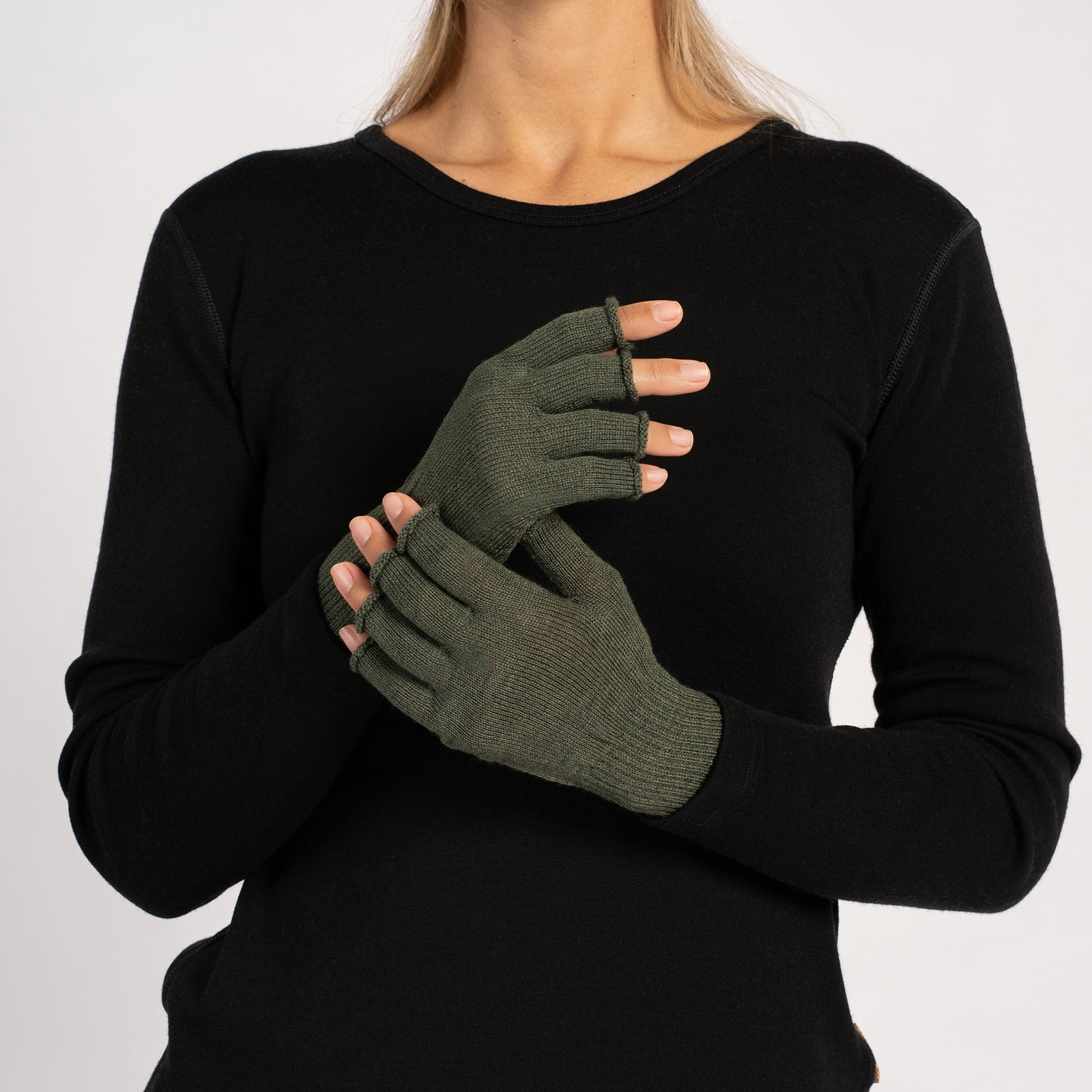 Primer plano de las manos de una mujer que lleva guantes sin dedos de merino color beige cremoso, con las palmas hacia adentro y los dedos visibles.