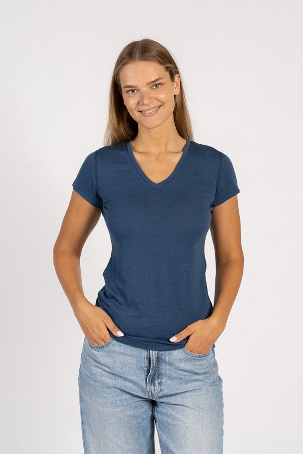 Mujer sonriendo con una camiseta de manga corta de lana merina azul vaquera y cuello en V.