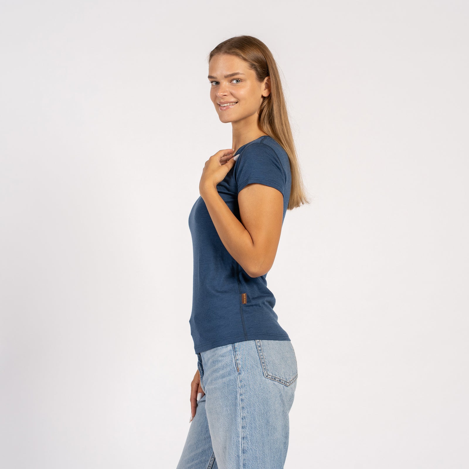 Mujer sonriendo con una camiseta de manga corta de lana merina azul vaquera y cuello en V.