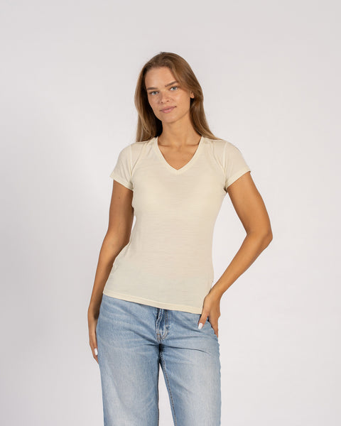 Mujer vistiendo una camiseta de cuello en V de lana merina de color natural con mangas cortas.