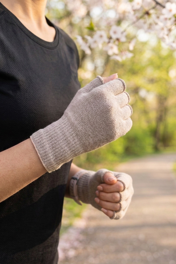 Woman running in spring park wearing beige merino wool fingerless running gloves, lightweight breathable gloves for temperature regulation and outdoor workouts