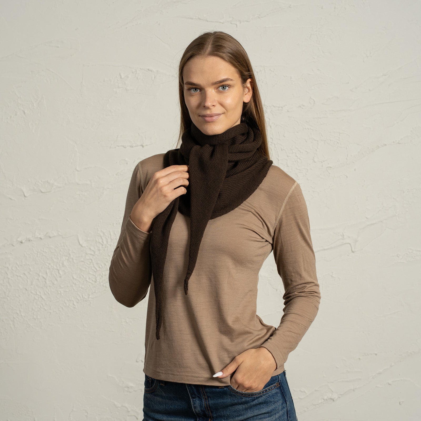 Primer plano de una mujer que lleva una bandana de lana merina marrón, usada como capucha y bufanda.