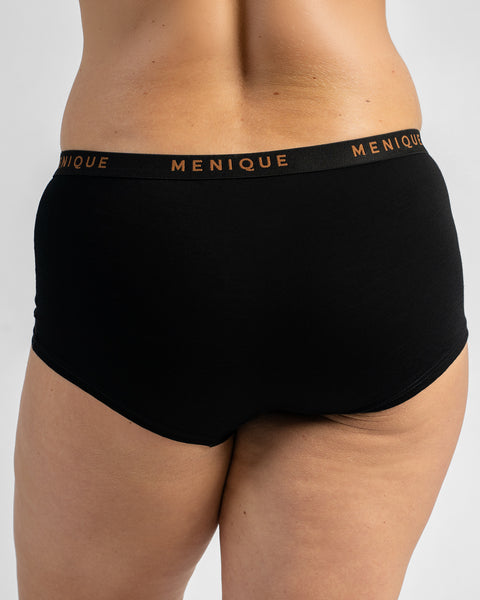 Back view of a model wearing black boy-short underwear with a black elastic waistband featuring text.