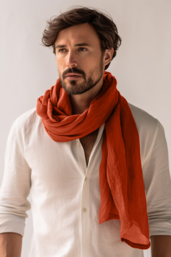 Hombre con camisa blanca y bufanda naranja sobre un fondo liso