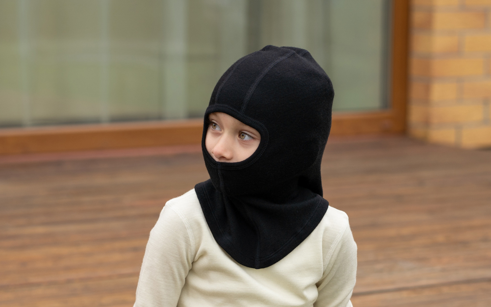 Una niña que lleva la braga de cuello menique de lana merina 250gsm en color negro.