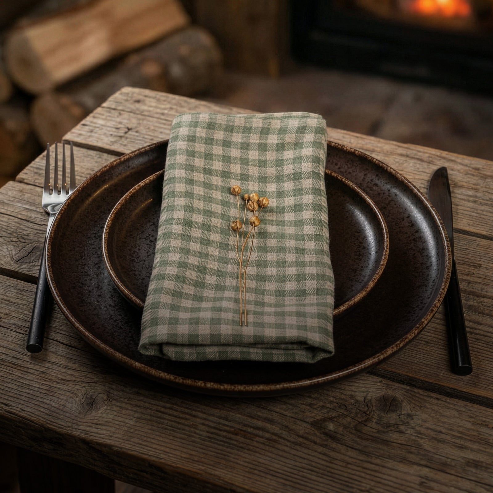 Mesa puesta con servilleta a cuadros, platos, tenedor y cuchillo sobre una superficie de madera.