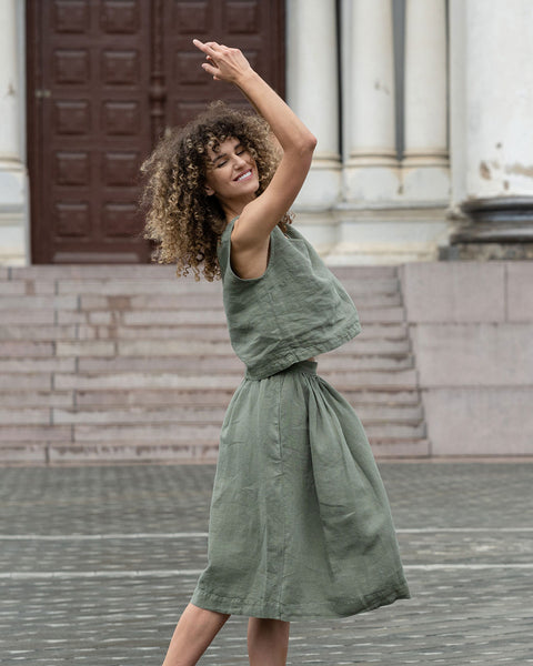 Mujer con peinado rizado posando en la ciudad, vistiendo un top corto verde piedra y una falda verde piedra Sophia.